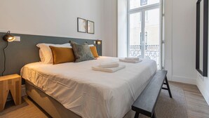 Un lit bien fait, avec des oreillers, une lampe de chevet et un banc.