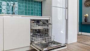 A kitchen with a dishwasher, a sink, and a teal backsplash. - Ando Living - Abrantes Flats - 31 (Lisbon)