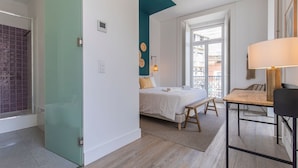 Une chambre à coucher comprenant un lit, une table de chevet, un banc et une fenêtre donnant sur l’extérieur.