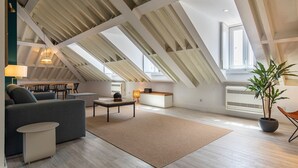 Un loft moderno con techos altos, tragaluces y un rincón de descanso acogedor con sofá y mesa de centro.