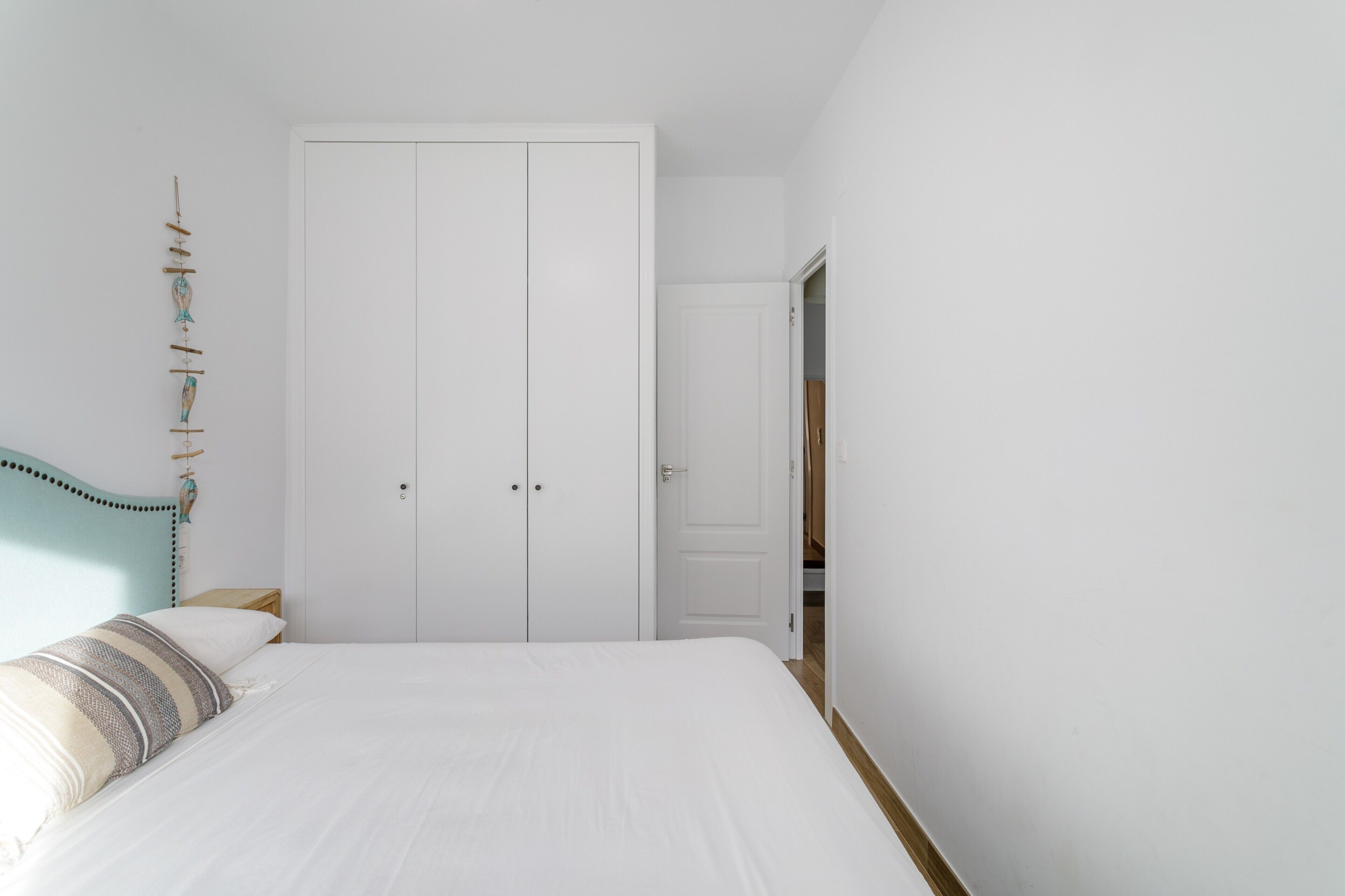 Un dormitorio con cama, armario y puerta que da a otra habitación.
