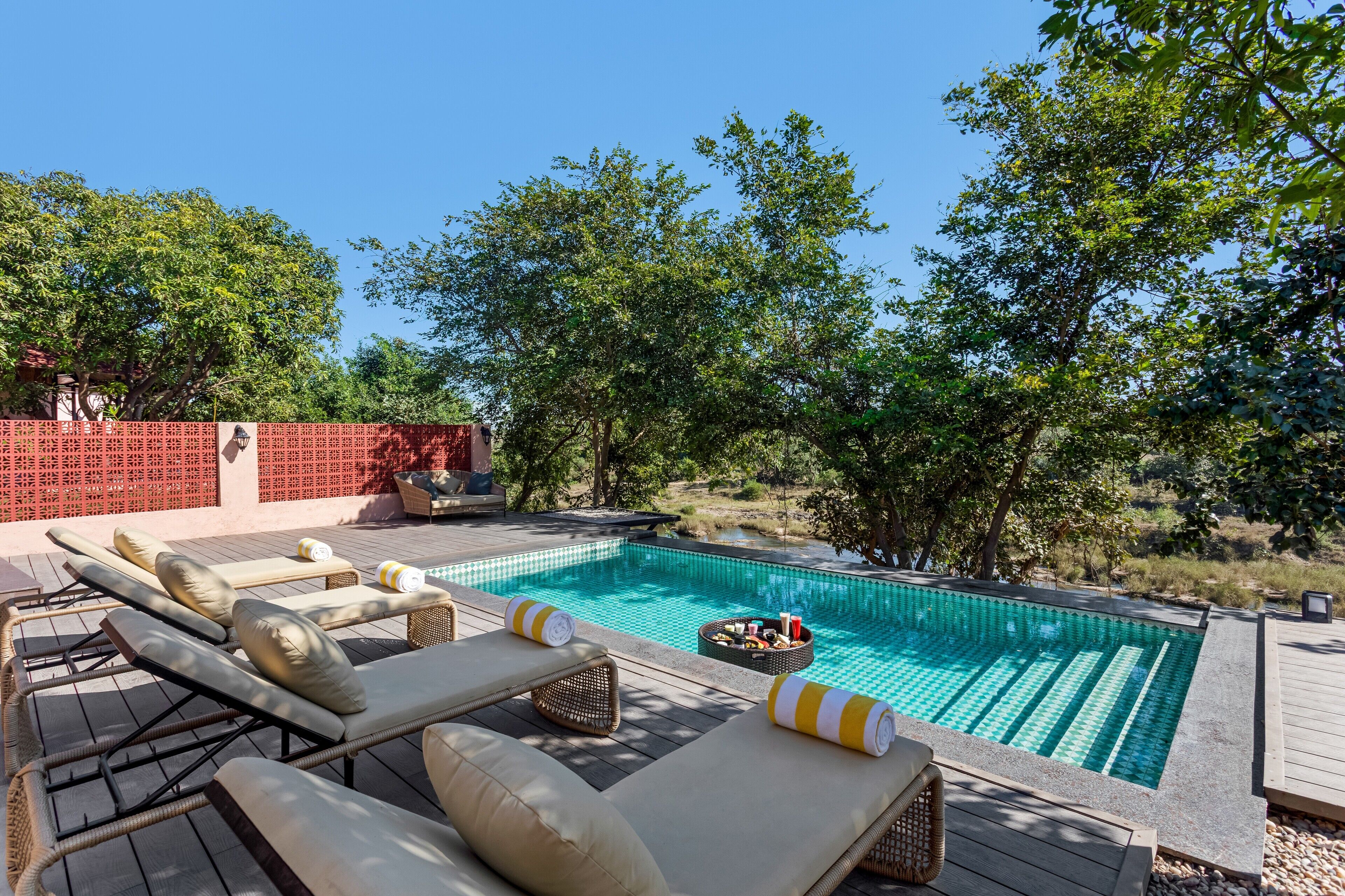 Zona de piscina con sillones de descanso y un pequeño hogar para fuego.