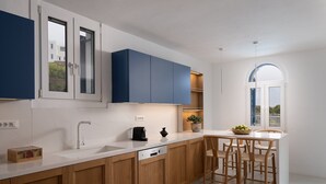 Eine moderne Küche mit Holzausstattung, einer weißen Arbeitsplatte und einem Essbereich mit Holzsesseln.