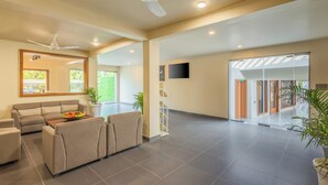 Un'ampia hall con un divano, una ventola a soffitto, una scala e una grande finestra.