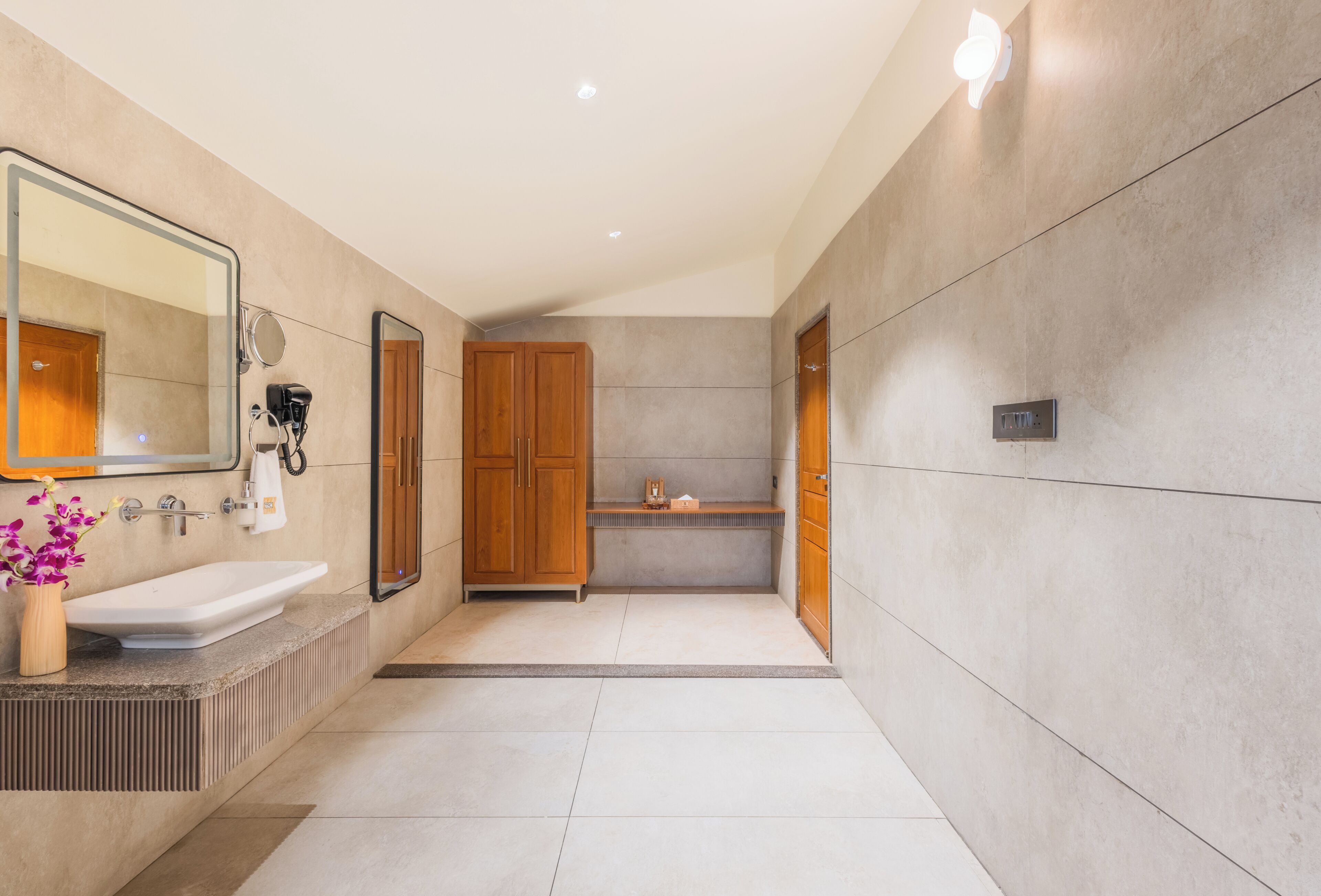 A modern bathroom with a large mirror, a sink, and a shower area.
