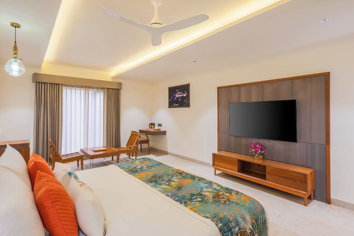 A hotel room with a bed, a desk, a chair, a TV, and a ceiling fan.