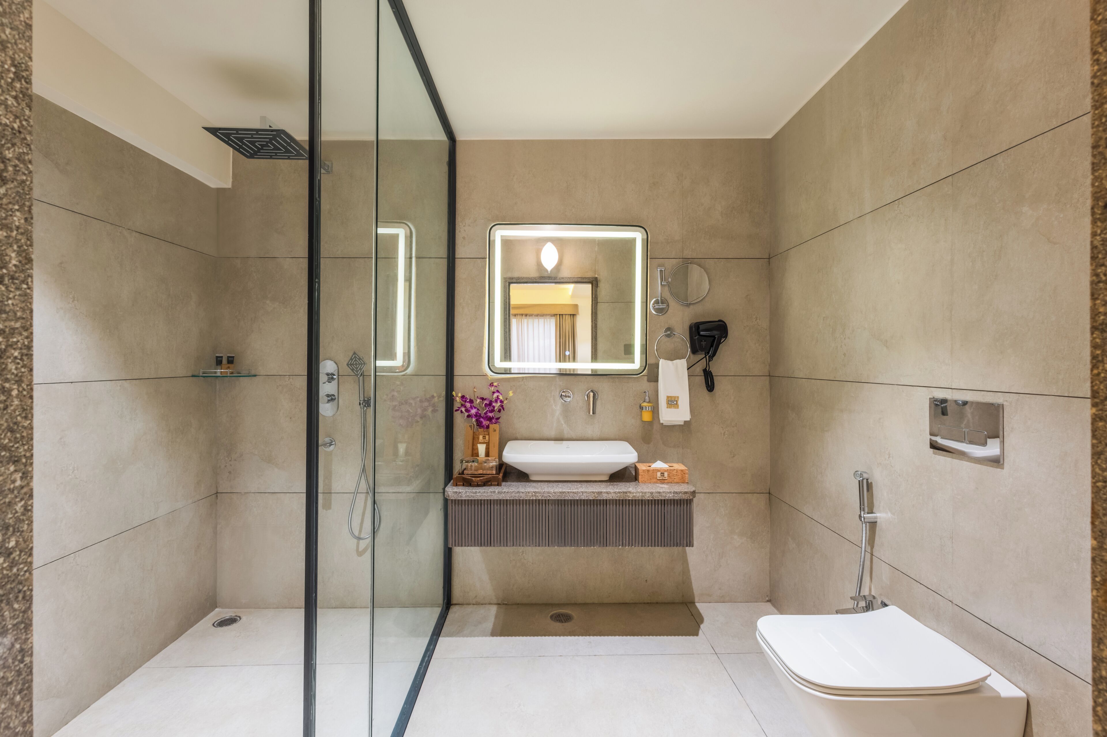Un baño moderno con cabina de ducha de vidrio, tocador con espejo y retrete.
