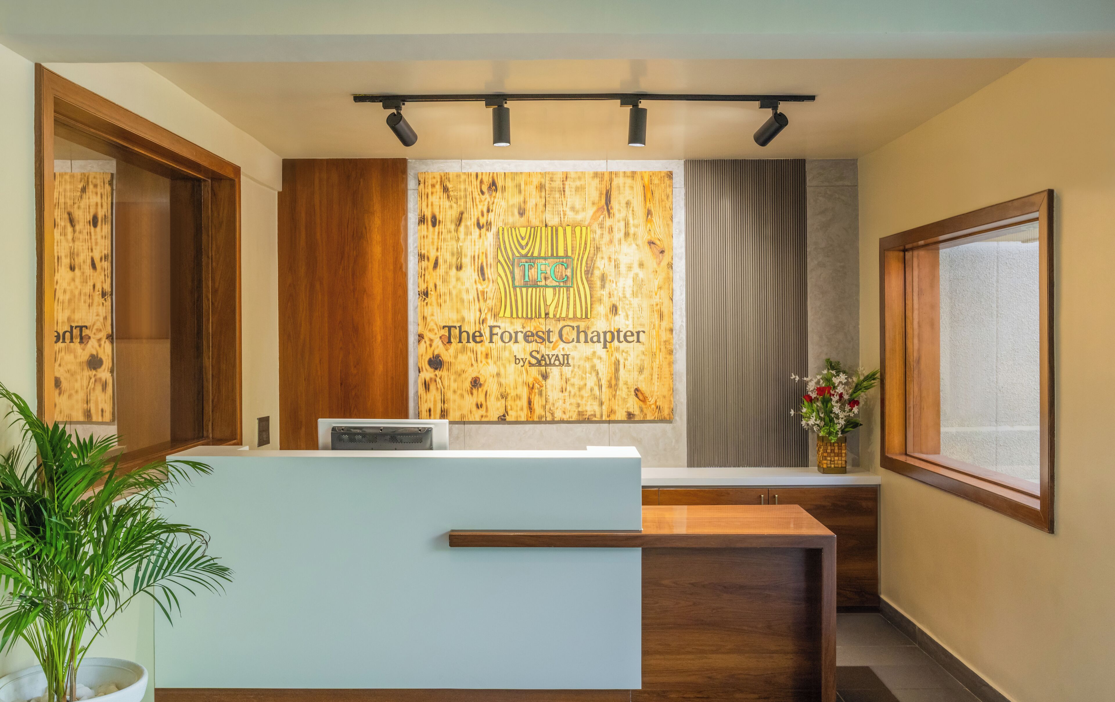 A reception desk with a wooden backdrop, a plant, and a window with a view.