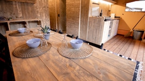 Een houten eettafel met placemats, kommen en een kleine plant.