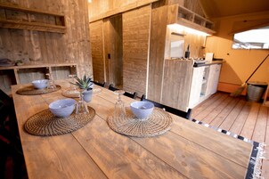 Una mesa de madera con manteles individuales, cuencos y una planta pequeña.