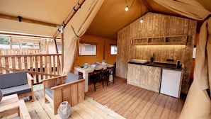 Een houten terras met een eethoek, een kleine kitchenette en een bank.