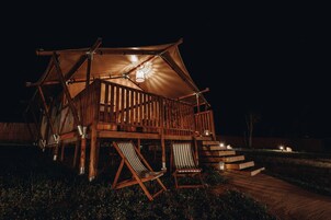 Una cabaña de madera con balcón y dos sillones de descanso.