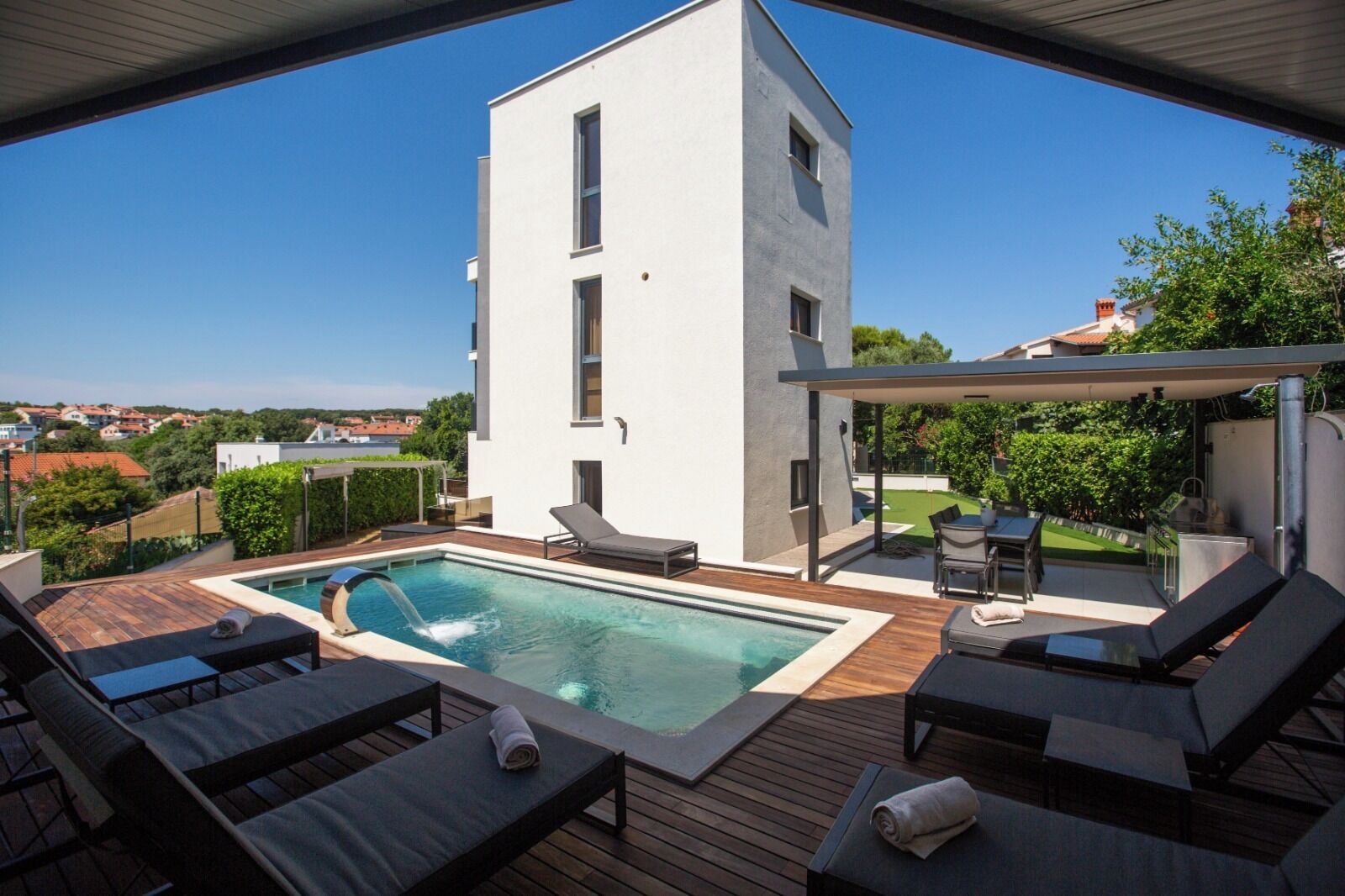 A modern outdoor pool area with lounge chairs and a pergola.
