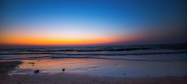 Una playa al atardecer con olas suaves lamiendo la orilla.