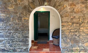 A stone archway leading to a room with a bed and a chair. - Manoribel (Mumbai)