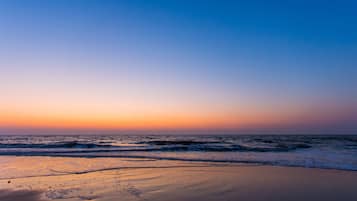 A beach at sunset with waves approaching the shore.