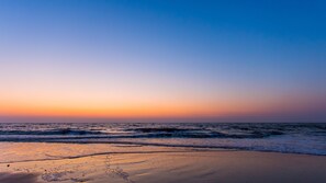 Una playa al atardecer con olas acercándose a la orilla.