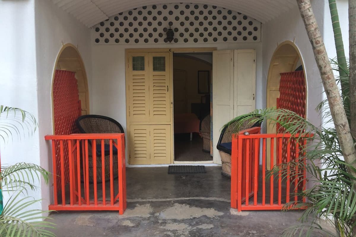 Une entrée d’immeuble avec une façade blanche, deux portes rouges et un plafond à pois.