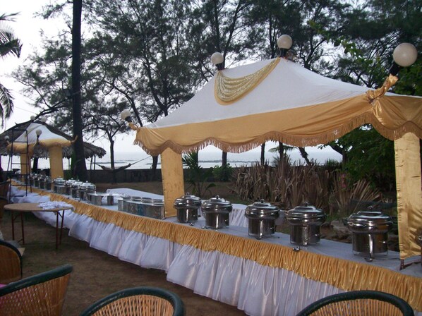 Montaje para un evento al aire libre con una mesa cubierta, sillas y recipientes para servicio de alimentos.