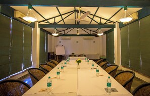 Un salón de conferencias con una larga mesa, sillas, botellas de agua y una pizarra.