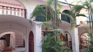 A courtyard with arches, a tiled floor, and potted plants. - Manoribel (Mumbai)