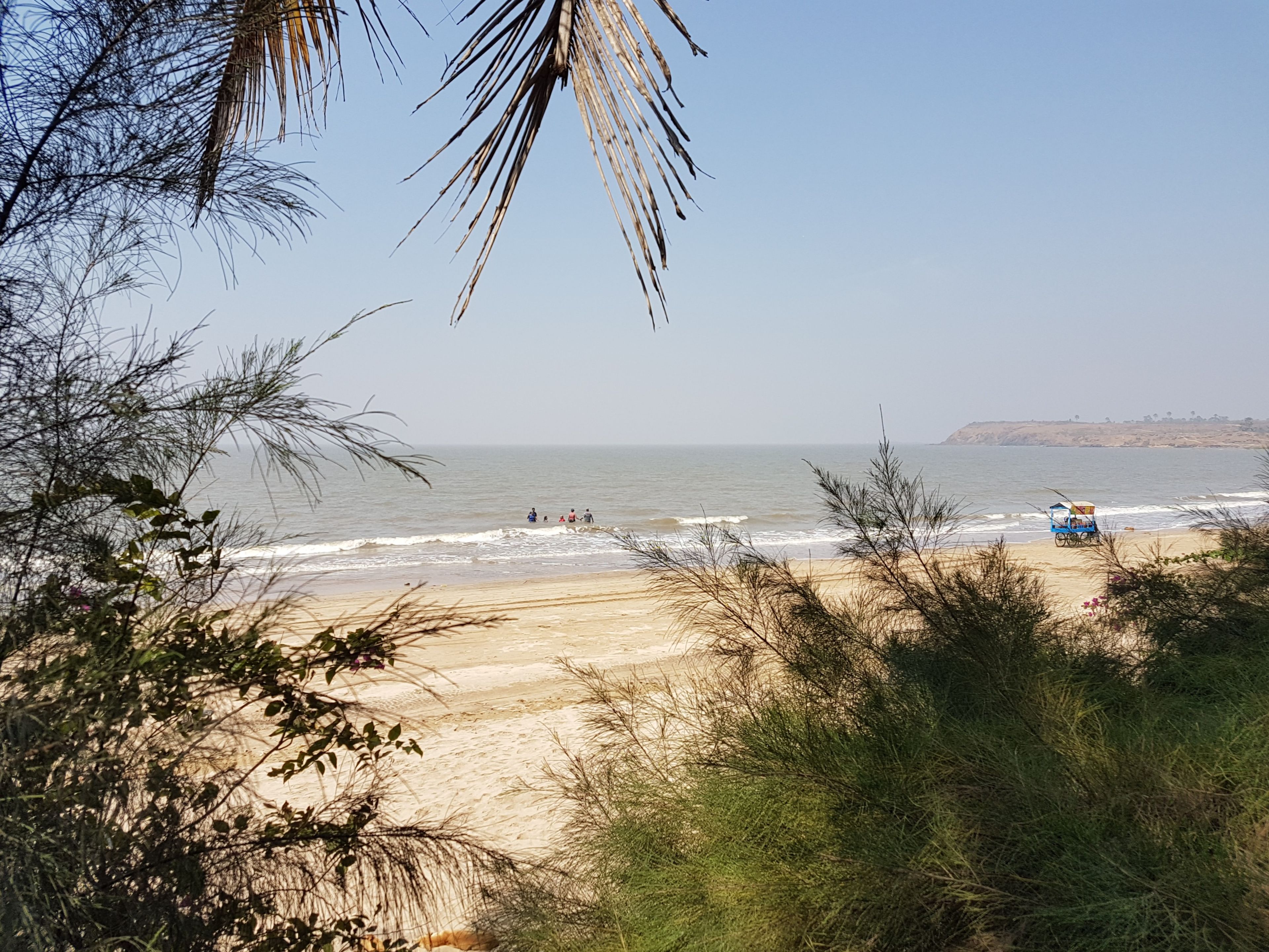 A beach with a clear sky, waves, and a distant hill.