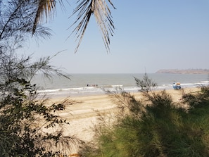 A beach with a clear sky, waves, and a distant hill. - Manoribel (Mumbai)
