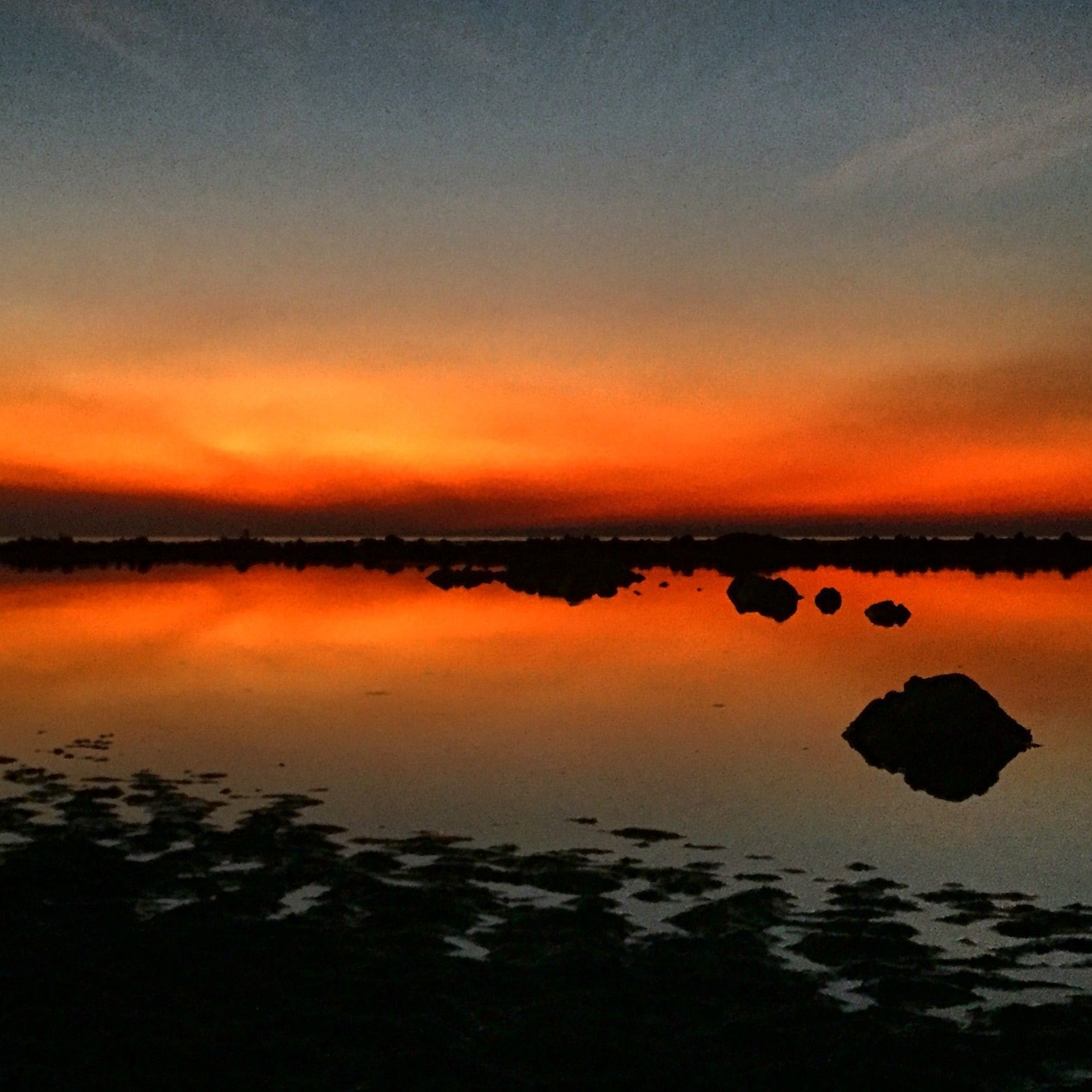 A calm body of water reflecting a sunset sky.