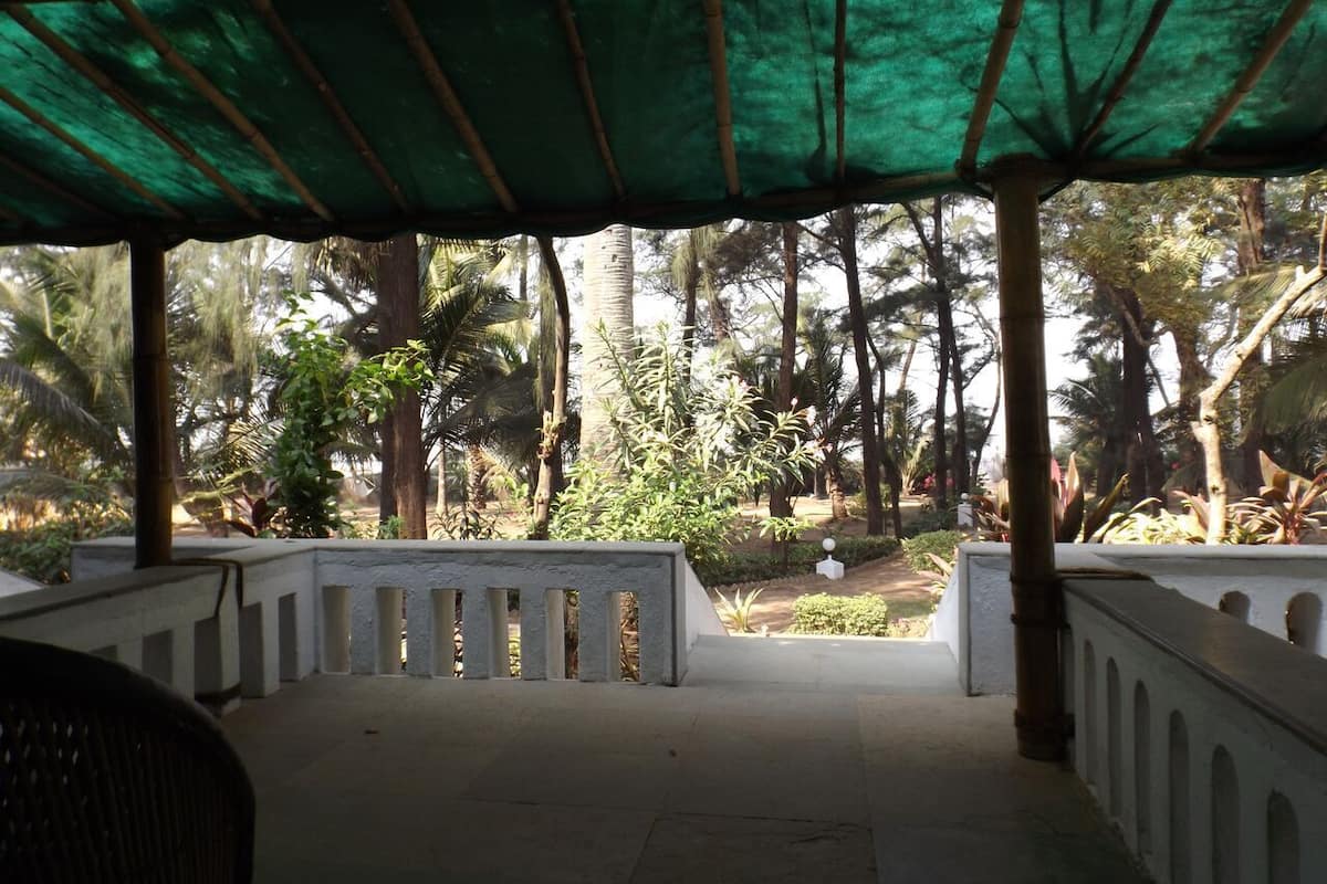 Un espace extérieur abrité, doté d’un banc et d’une rambarde en béton, et entouré d’une végétation tropicale.
