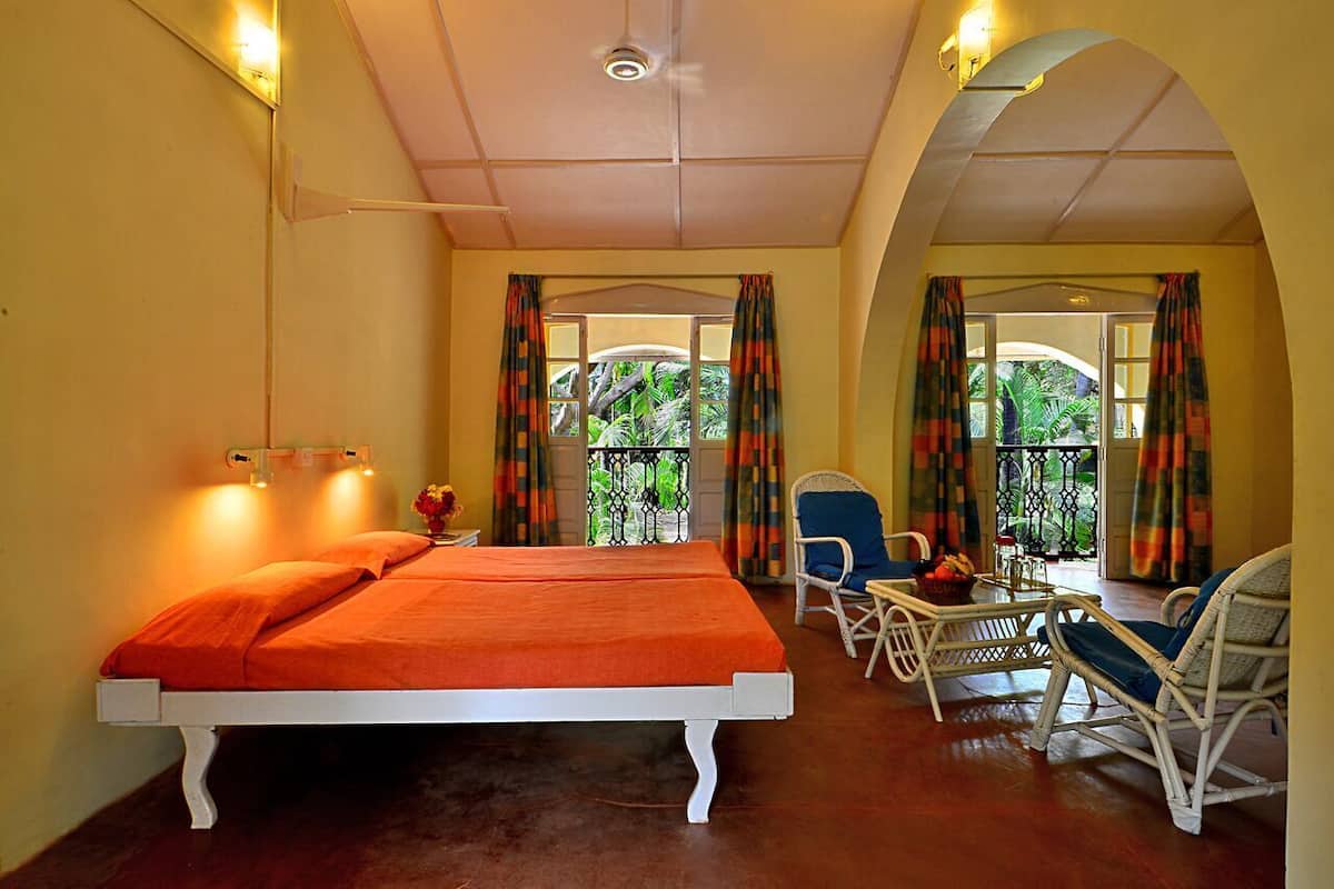 Une chambre avec un lit, une chaise, une table et un balcon avec des rideaux.