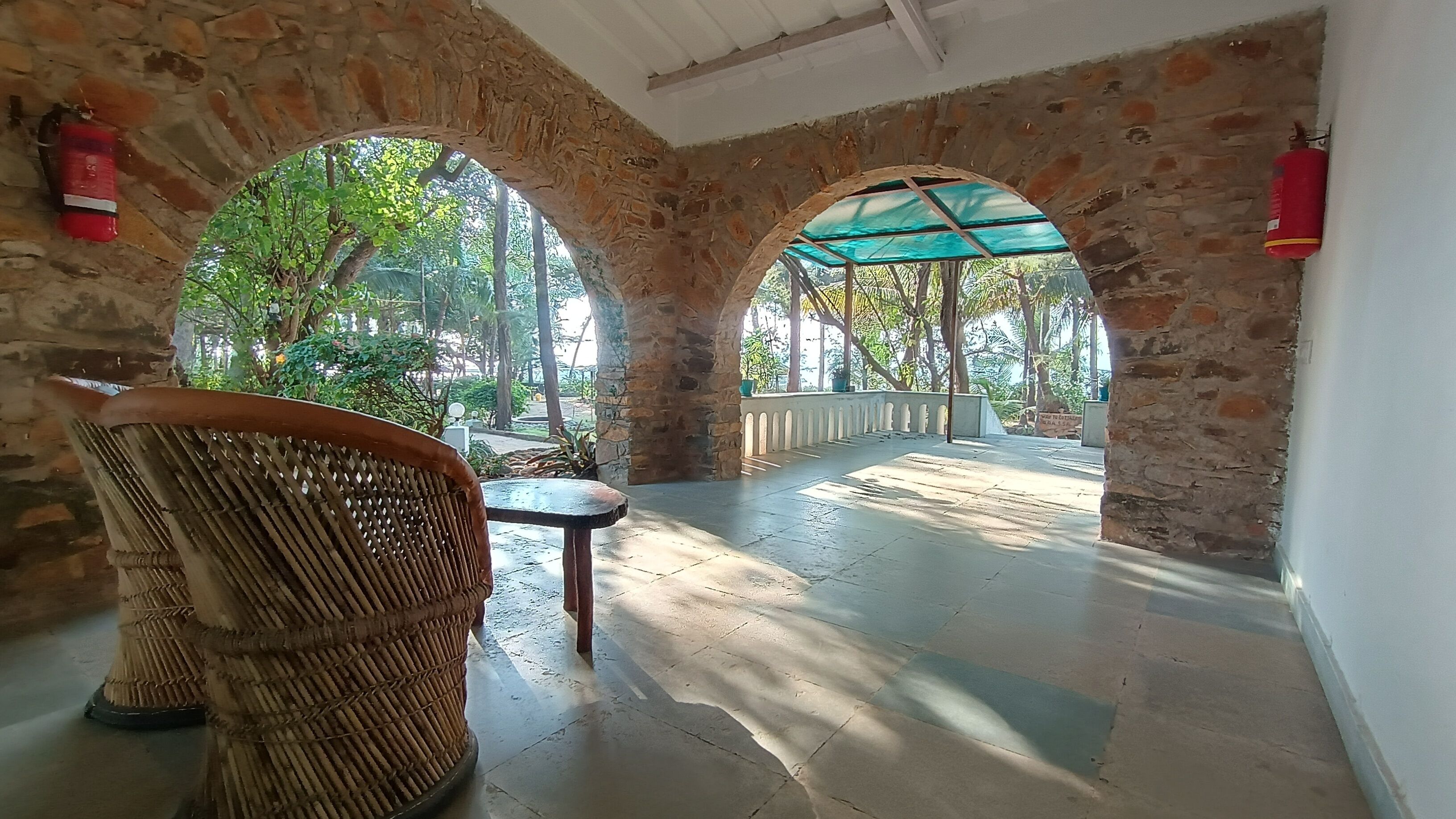A covered outdoor area with stone walls, a wicker chair, and a table.