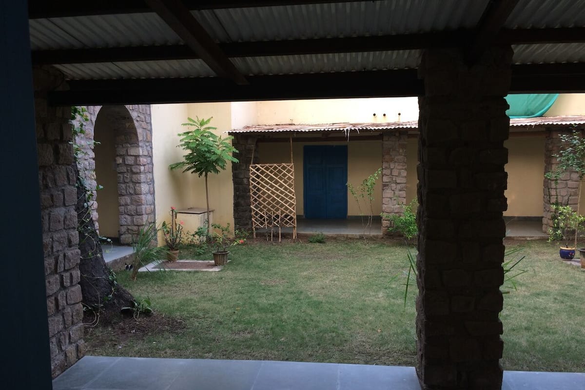 Une cour avec un mur en pierre, une porte bleue et des plantes en pot.