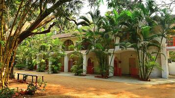 A colonial-style building with arched windows and a courtyard surrounded by lush greenery and palm trees.