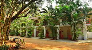 Un bâtiment de style colonial, doté d’arches au niveau des fenêtres et d’une cour intérieure bordée d’une végétation luxuriante et de palmiers.