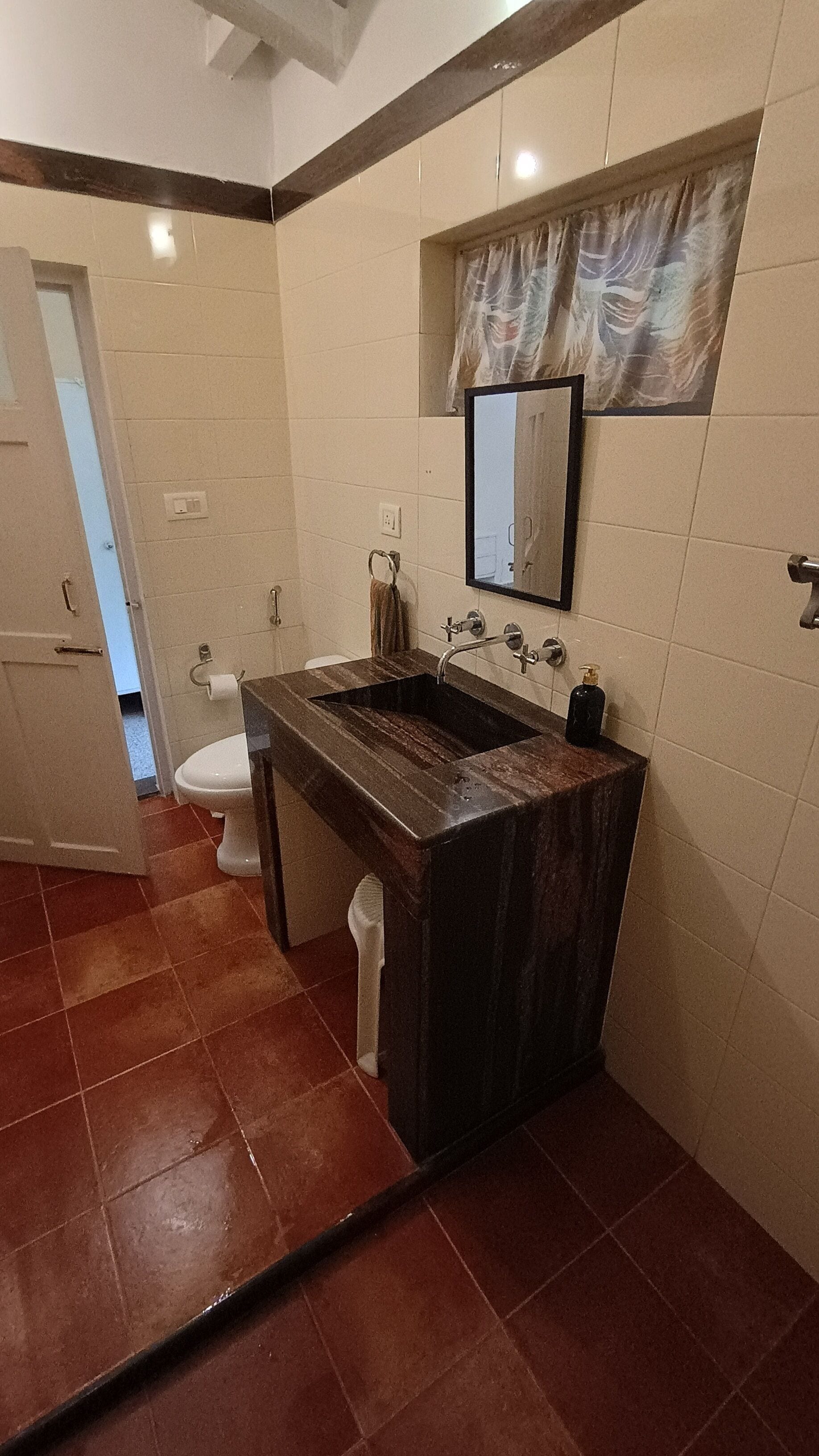 Een badkamer met een donker houten wastafelmeubel, een toilet en een spiegel boven de wastafel.