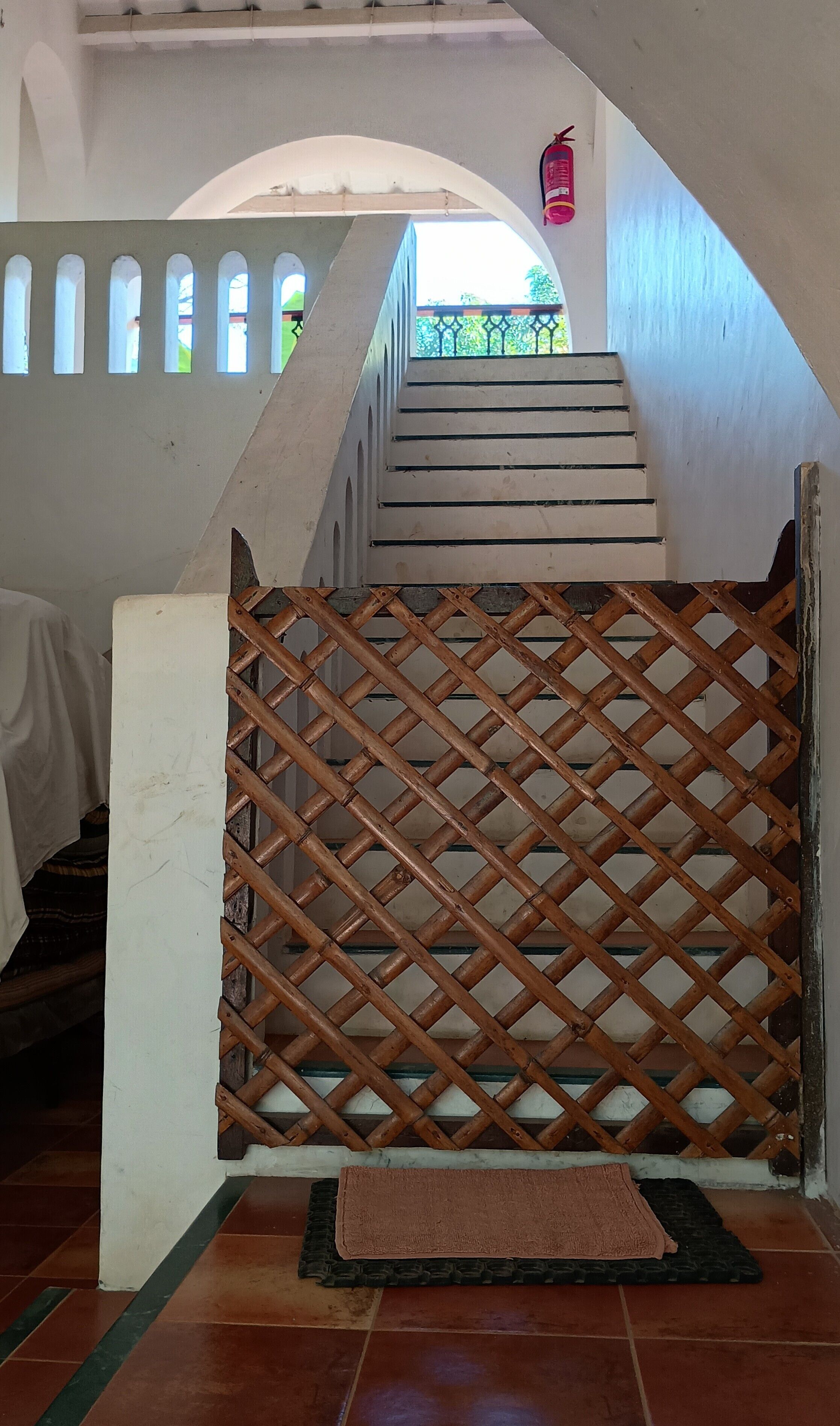 A staircase with a wooden lattice barrier at the bottom, leading to an upper level.