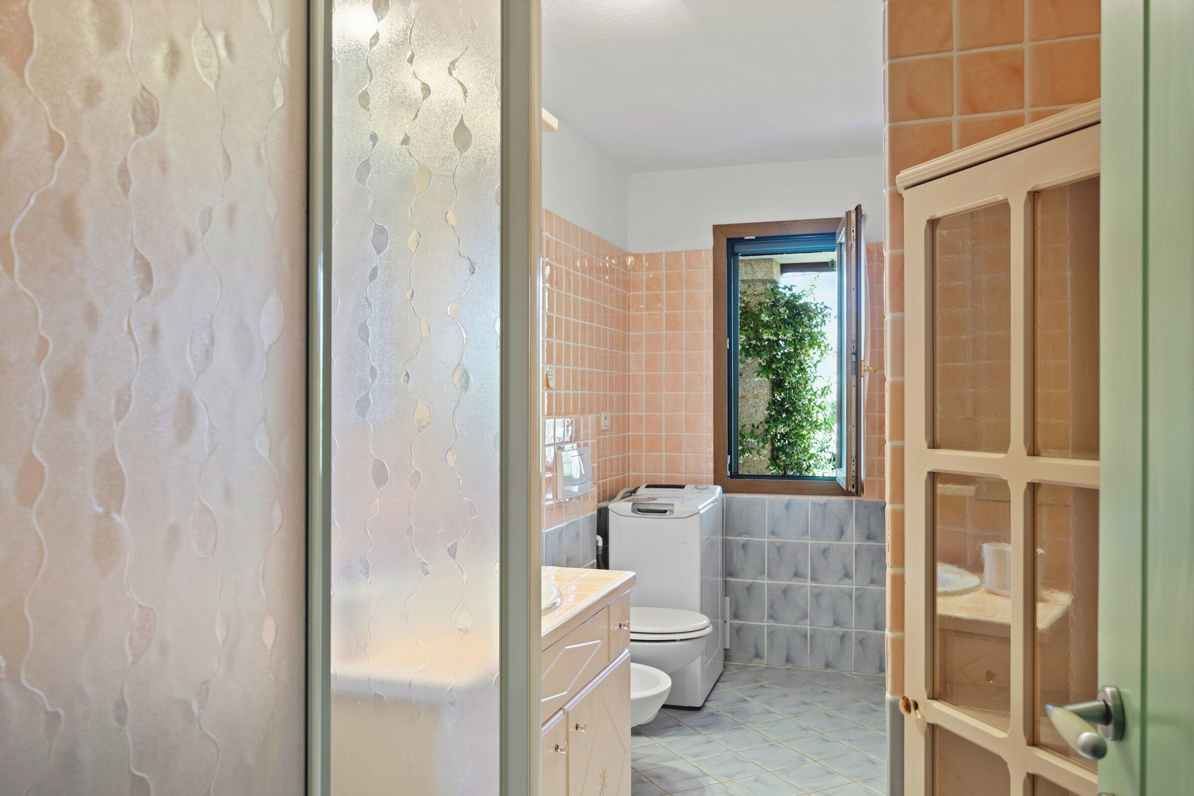 A bathroom with a toilet, sink, and window.