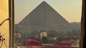 A view of a pyramid from a window with two wicker chairs. - King Khufu suite (Giza Governorate)