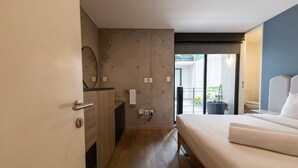 Un dormitorio con cama, cómoda, espejo y puerta que da a un balcón.