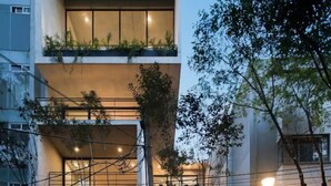 Un edificio moderno de varios pisos con balcones, ventanas amplias y plantas en el exterior.