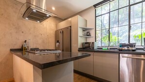 Una cocina moderna con una isla central, electrodomésticos de acero inoxidable y un amplio ventanal con vistas a zonas verdes.
