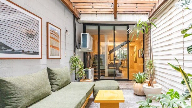 Un espacio interior acogedor con un sofá verde, una mesa de madera y plantas en macetas.