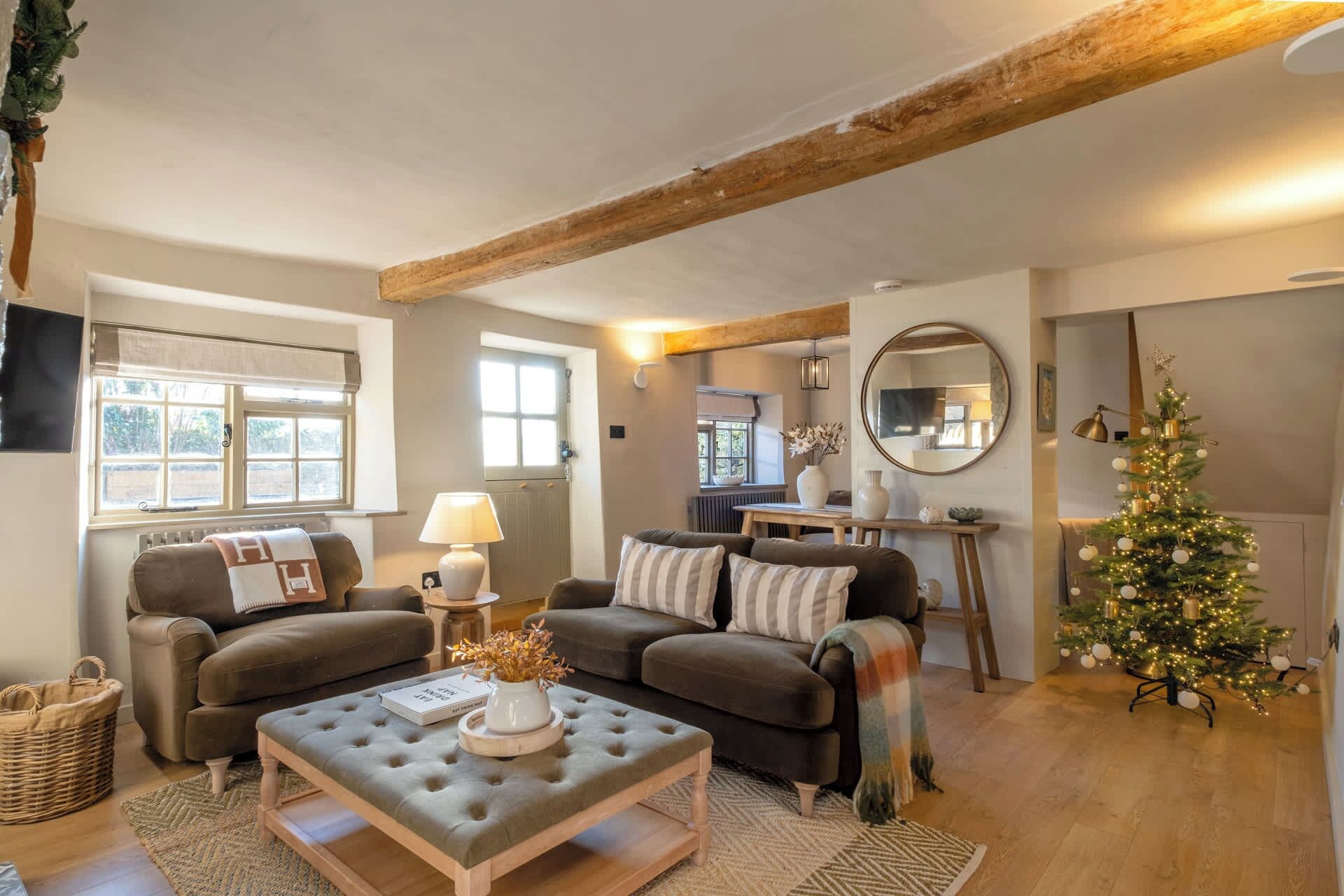 A cozy living room with a fireplace, a Christmas tree, and a dining area.