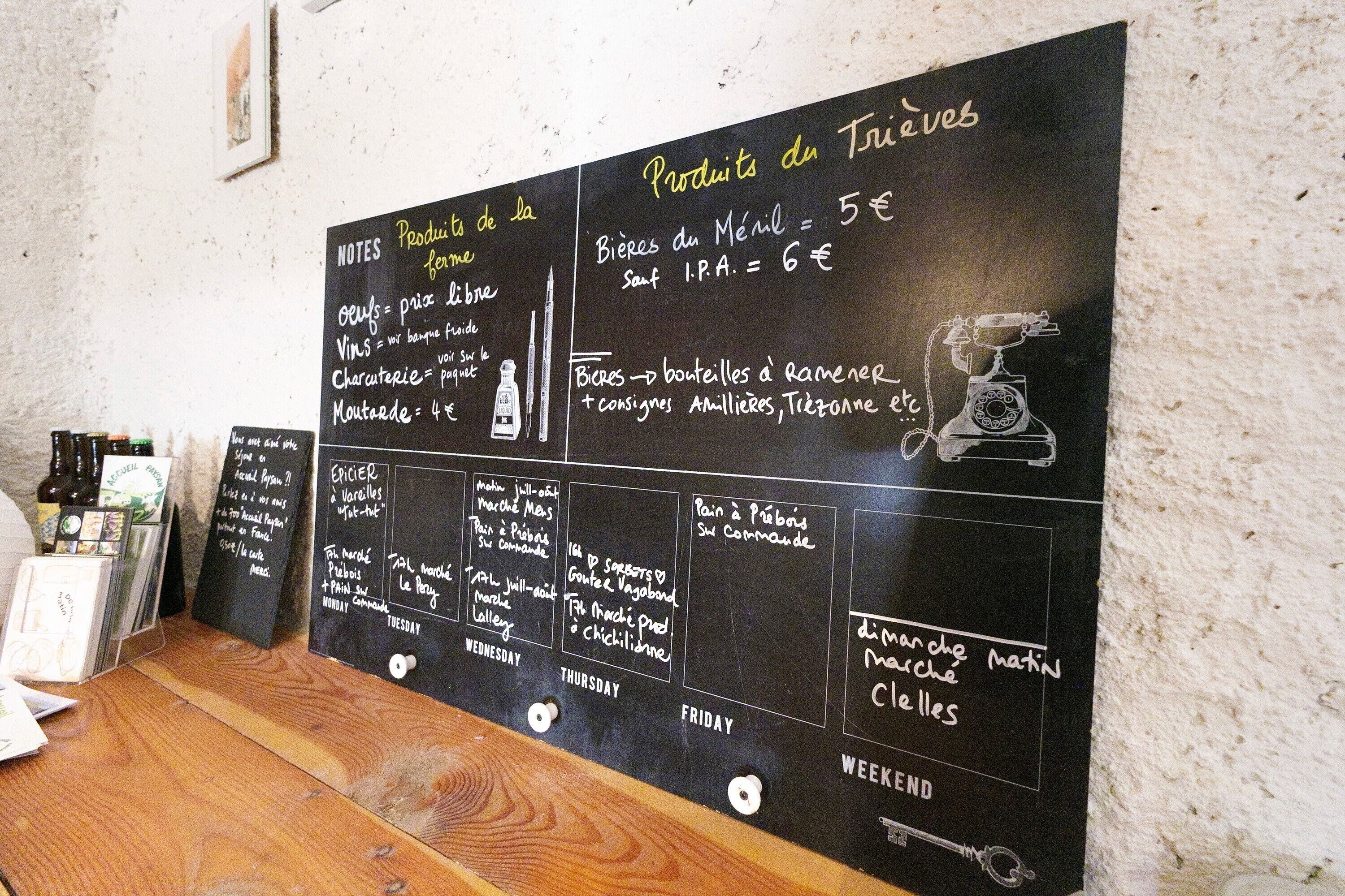 A chalkboard menu with daily specials and prices, a wooden table, and a wall-mounted corkboard with notes.