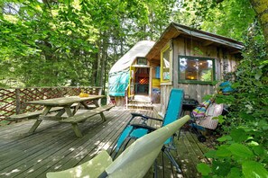 A wooden deck with picnic tables, a covered seating area, and a small cabin with a porch. - Kyrgyz Yurt in the Forest – Farm Stay (Prébois)