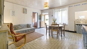 Un soggiorno con un divano, un tavolo da pranzo con sedie, un tappeto decorato e una ventola a soffitto.