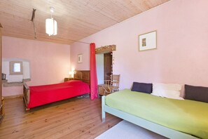 A bedroom with two beds, wooden flooring, a mirror, and a window. - Farm Stay with Mountain Views, Animals, and Organic Wine Tasting (Prébois)