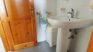 Un baño con puerta de madera, un lavamanos blanco y un inodoro.