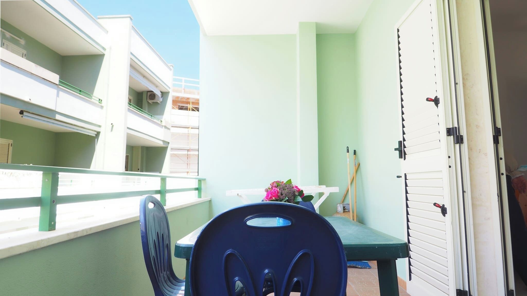 A balcony with a table, chairs, and a bouquet of flowers.