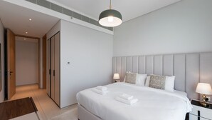 A modern hotel room with a large bed, bedside tables, a headboard, and a hanging light fixture. - Address JBR 2BR Steps to Beach Bluewaters (Dubai)